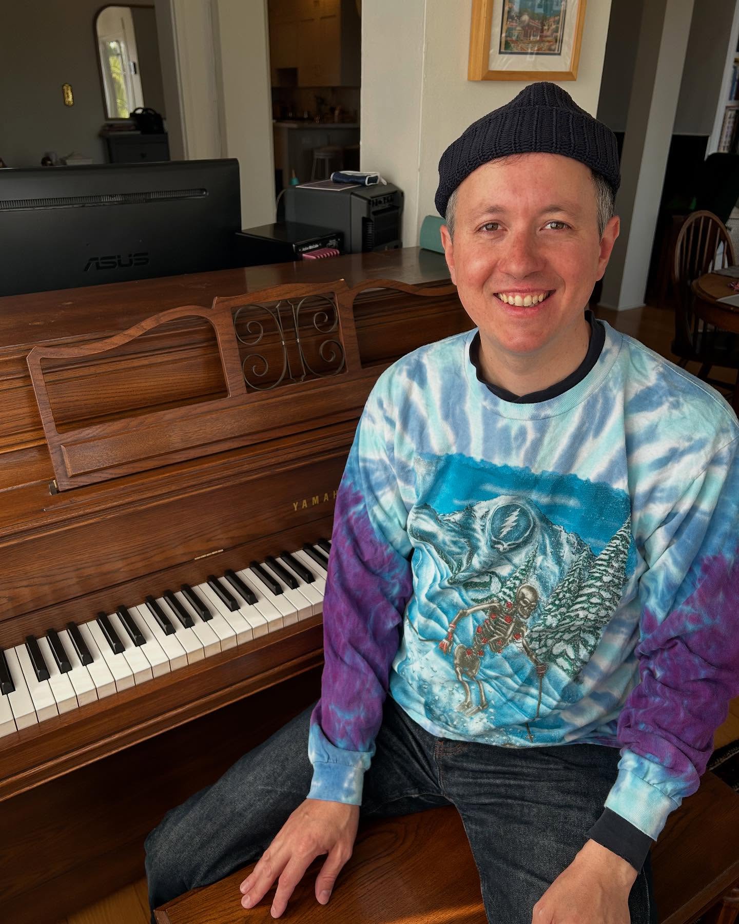 Brian Bond smiling while seated at a Yamaha upright piano