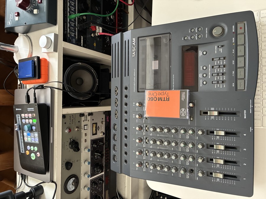 Tascam Portastudio 424 cassette four-track recorder in front of racks of outboard gear