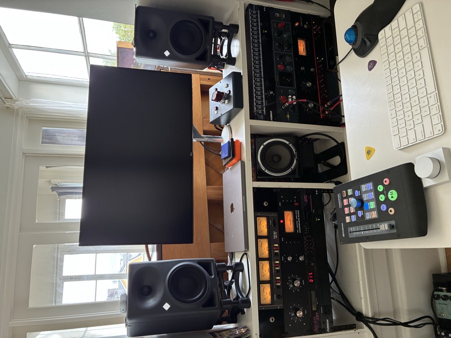 Rack of vintage outboard compressors and processors beneath a pair of studio monitors