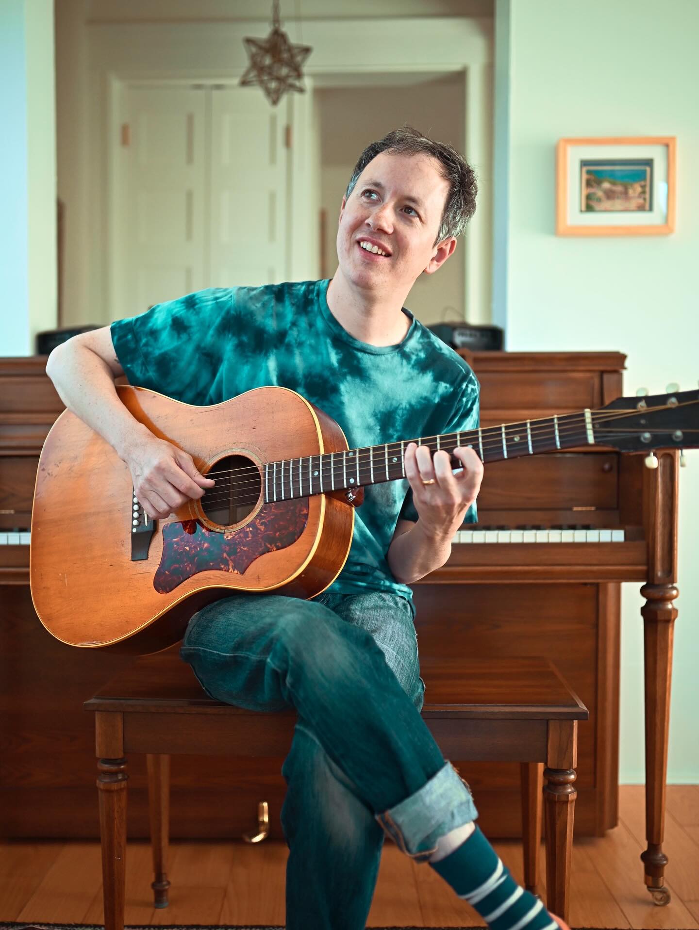 Brian Bond smiling and playing an acoustic guitar